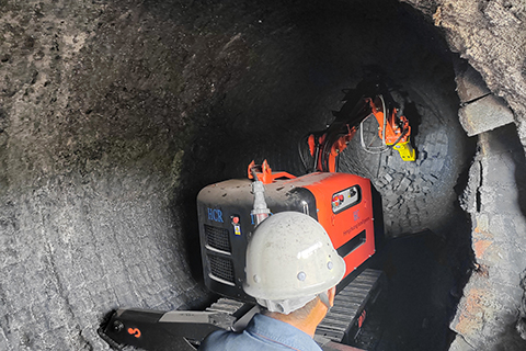 Hitech's demolition robot inside a steel mill torpedo car for refractory cleanout. The robot is remotely operated for safety.