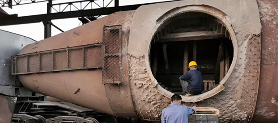 Worker inspecting the interior of a torpedo car through a roof opening