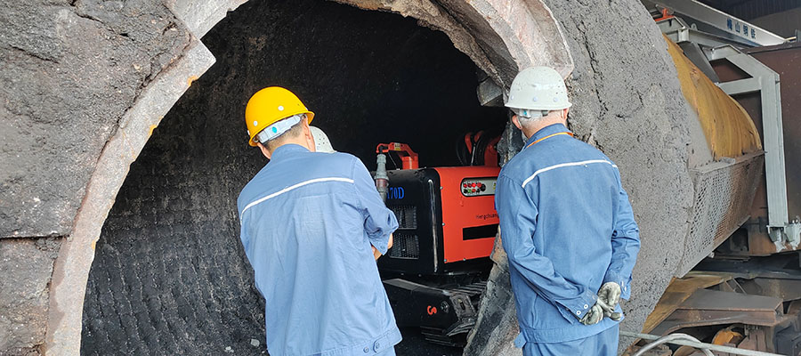 Demolition robot performing refractory demolition inside a torpedo car. The compact size allows access through torpedo car roof openings.