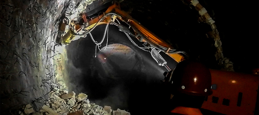 A compact demolition robot equipped with a pneumatic chisel chips away at the refractory bricks covering the inside of a cement kiln.