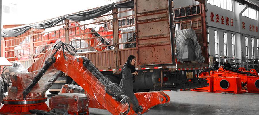 A heavy duty demolition robot specially equipped to dismantle refractory kiln bricks is strapped down in the truck bed, ready for shipping to the cement plant.