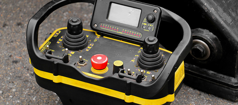 A close up of the handheld controller with joystick and buttons used by workers to steer and operate the jackhammer arm on a robotic brick dismantling system.