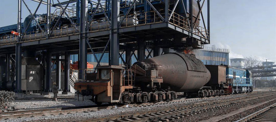 Large metal torpedo car on rails used for transporting molten metal at a steel mill. Refractory lining must be demolished and replaced periodically.