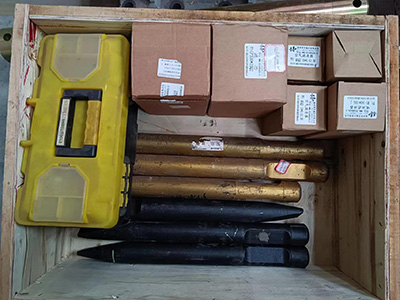 A warehouse worker using a pallet jack to move pallets loaded with the HCR120C Demolition Robot packaging and accessory kits.